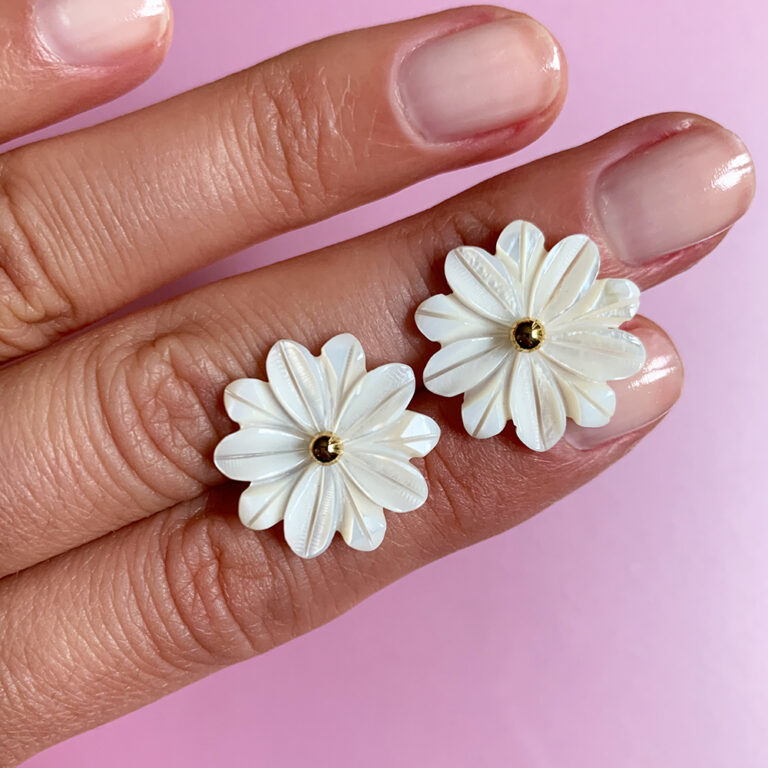 white flower earrings on hand